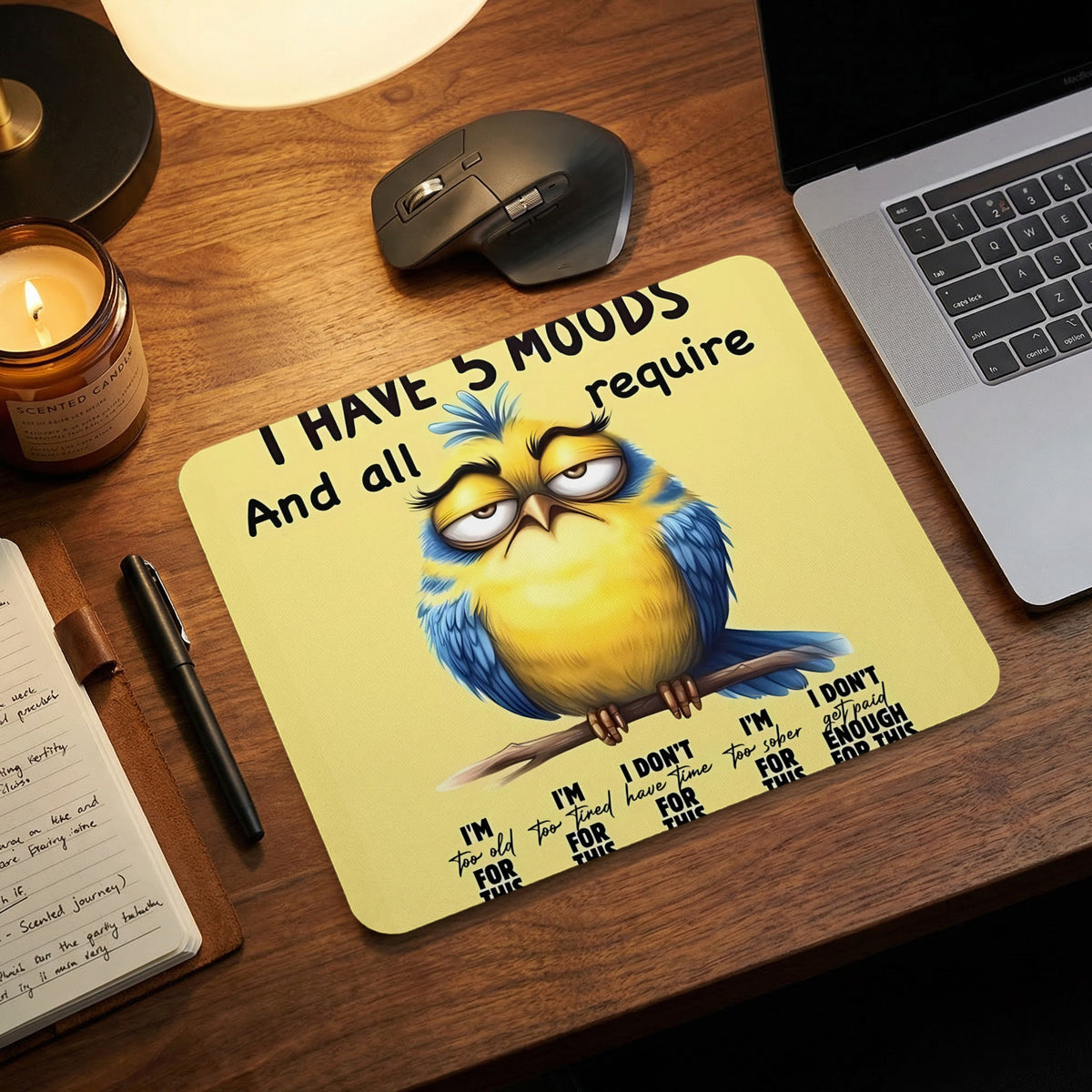 Yellow and blue mousepad featuring a grumpy bird and humorous text on a wooden desk setup.