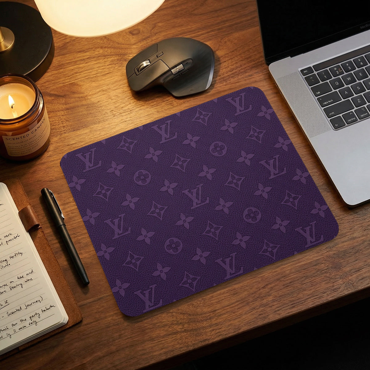 Purple mousepad with a recurring monogram pattern next to a laptop and mouse.