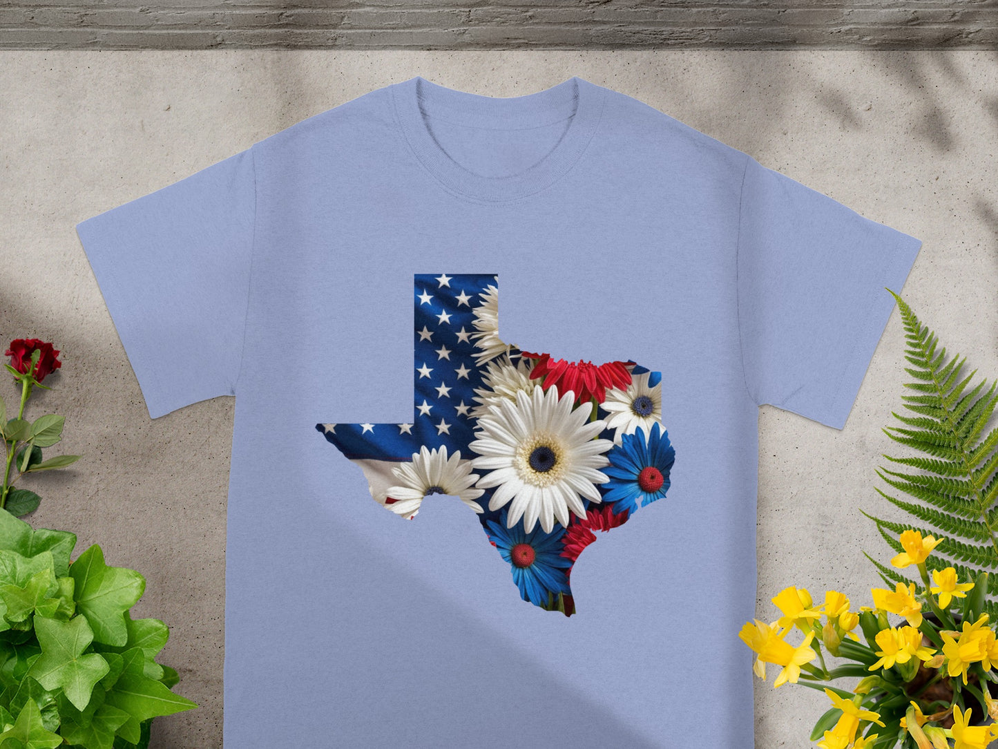 Light blue t-shirt with Texas map outline filled with US flag and flowers.