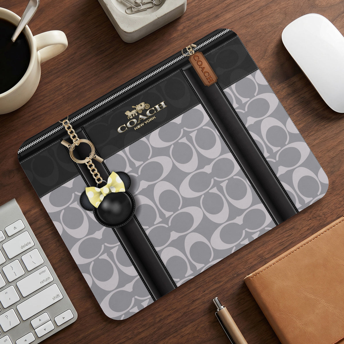 Coach laptop sleeve with gray signature pattern and Mickey Mouse charm.