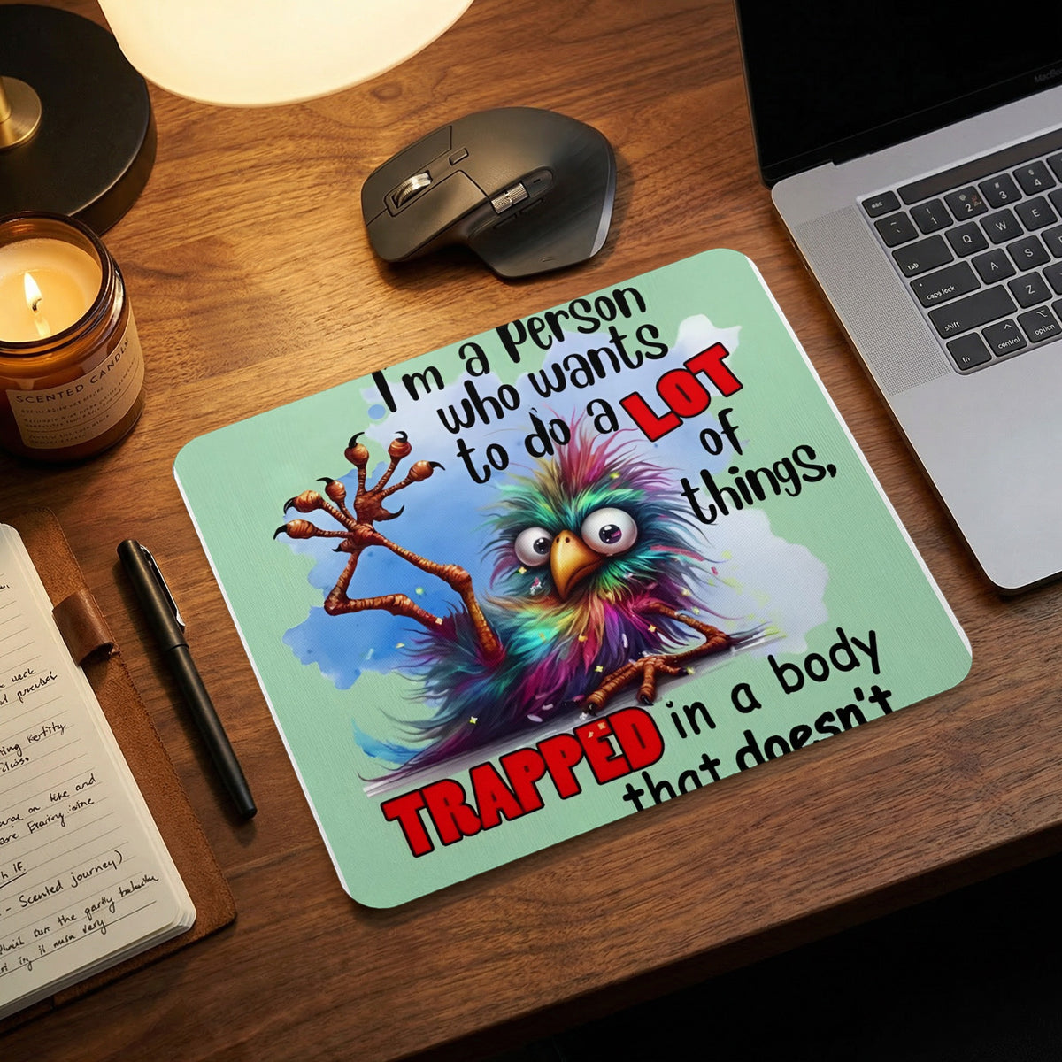 Light green mouse pad featuring a colorful, wide-eyed creature and text on a wooden desk.