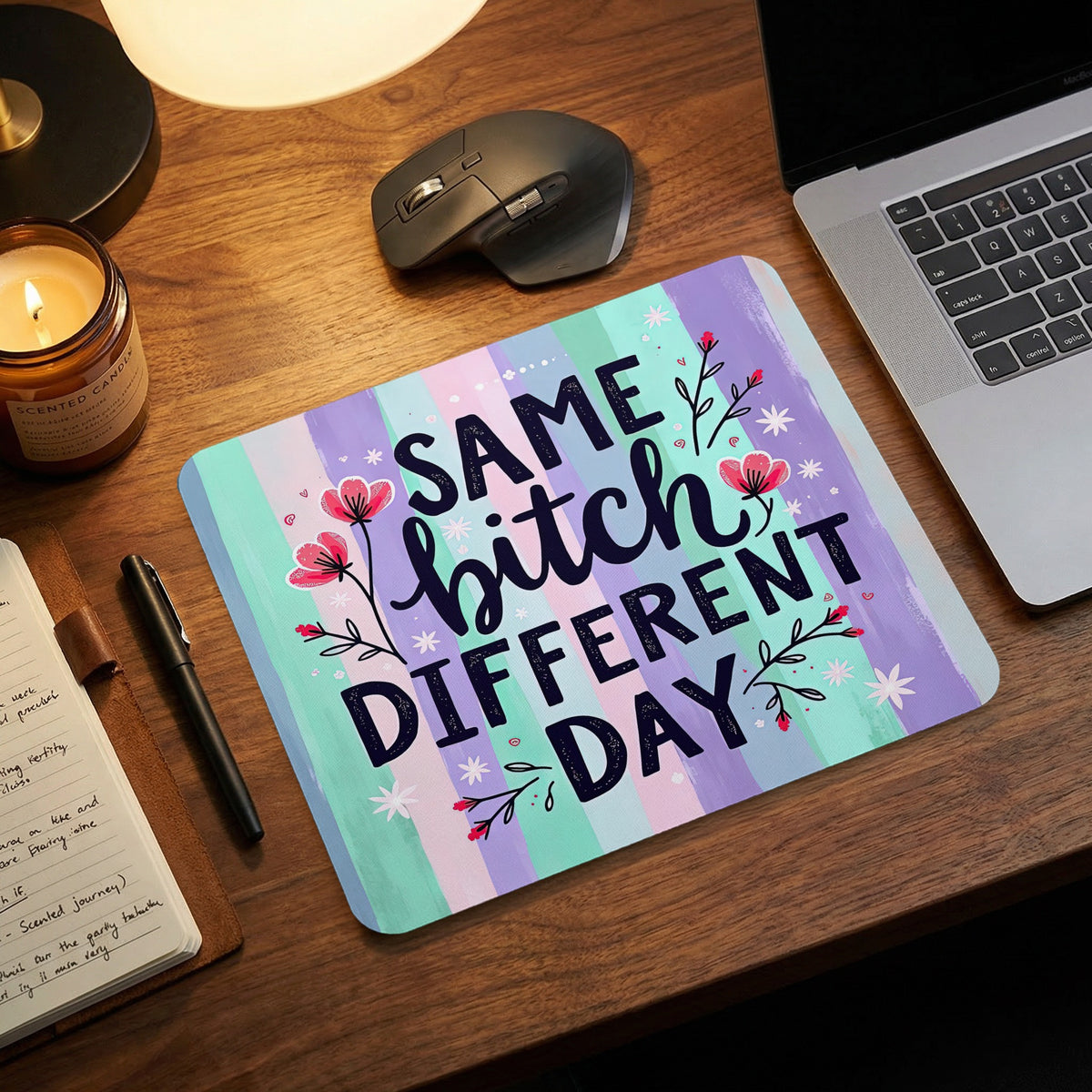 Rectangular mouse pad with purple and teal vertical stripes and the text Same Bitch Different Day on a wooden desk.