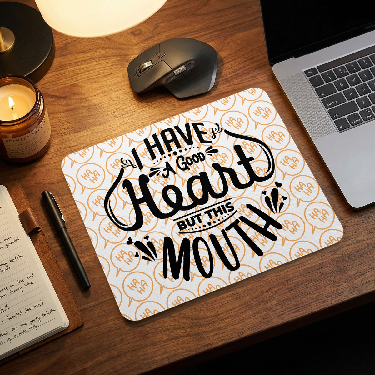Rectangular mousepad with black text I HAVE A GOOD HEART BUT THIS MOUTH on a background of orange speech bubbles with "HA HA" text.