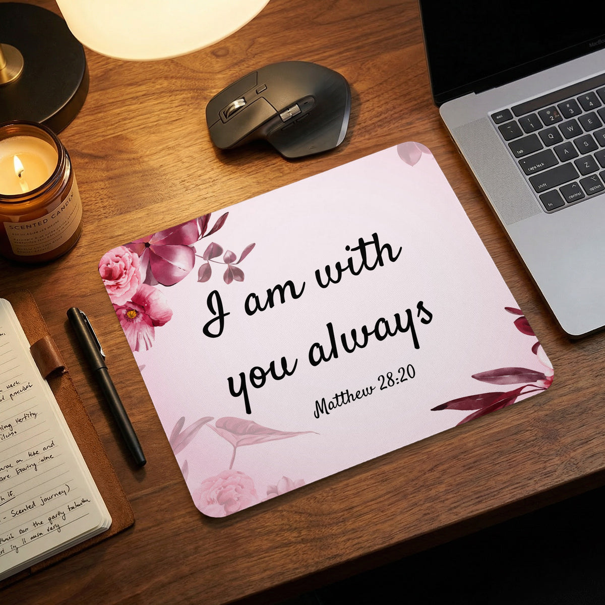Light pink mousepad featuring floral decorations and the black text I am with you always Matthew 28:20 on a wooden desk.