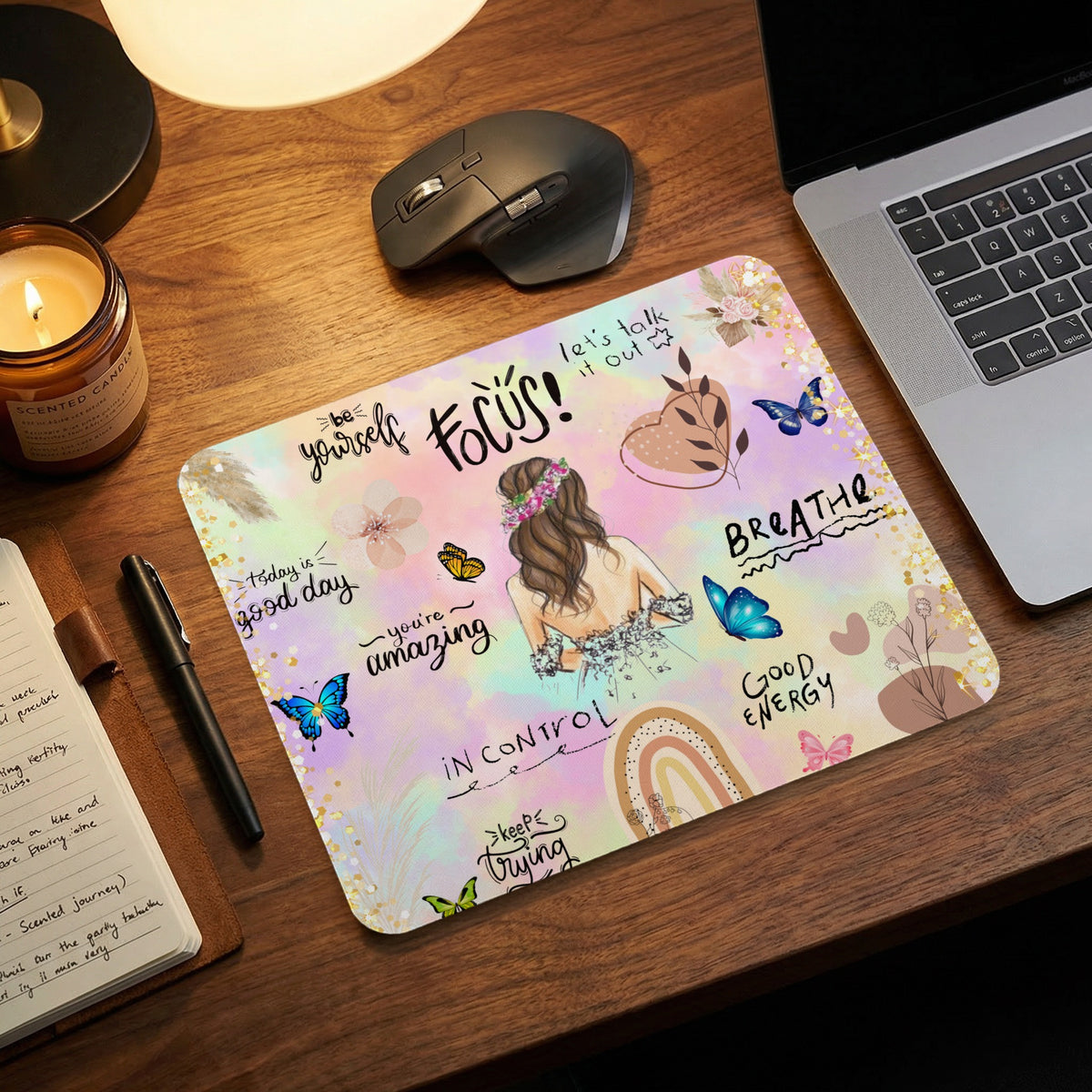 A rectangular desk mat with pastel watercolor background, motivational text, and illustrated butterflies on a wooden desk.