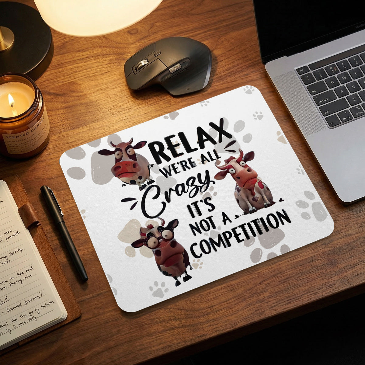 A white mouse pad with a cow design and the text Relax We're All Crazy It's Not A Competition.