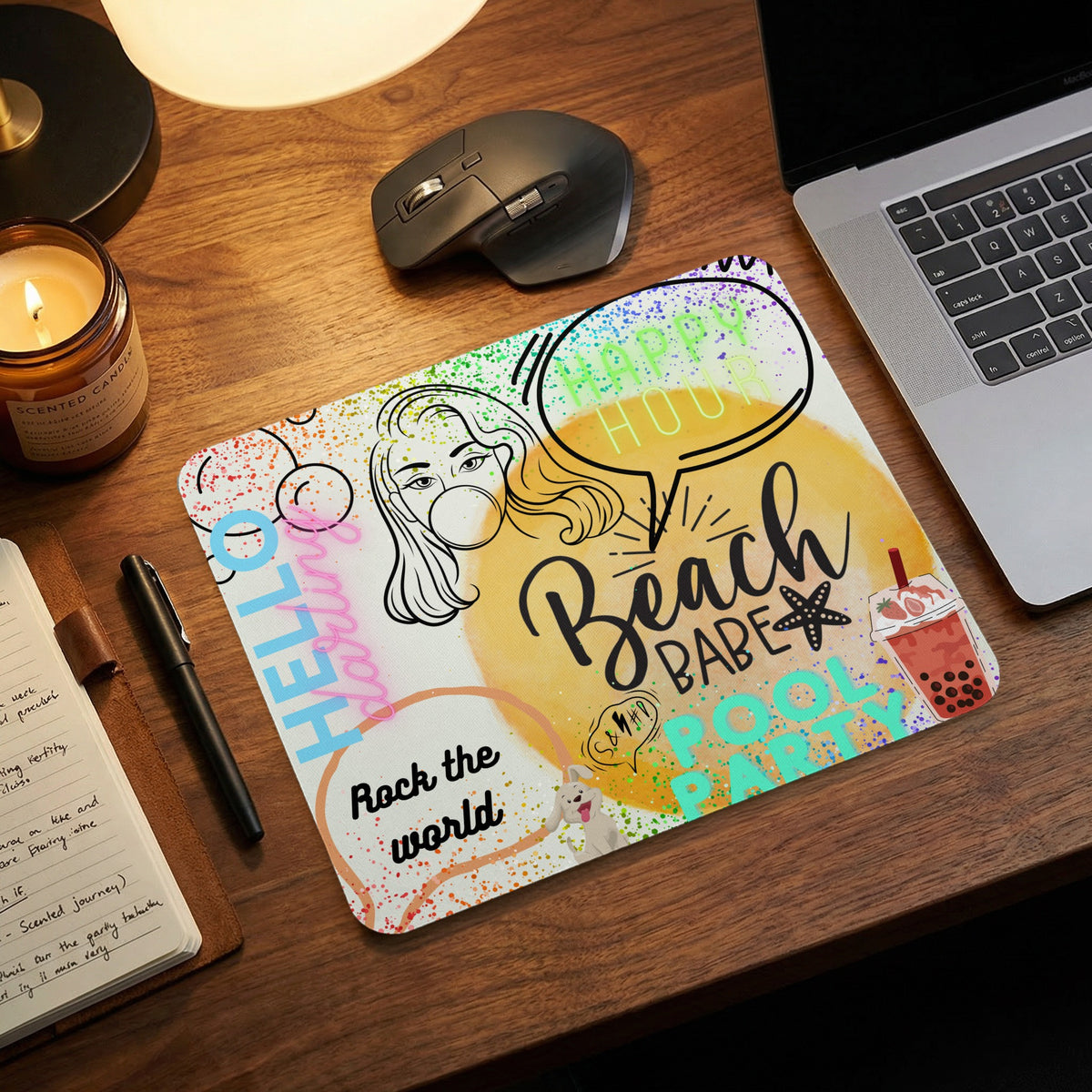 A colorful mouse pad on a wooden desk featuring playful text, doodles, and a laptop.