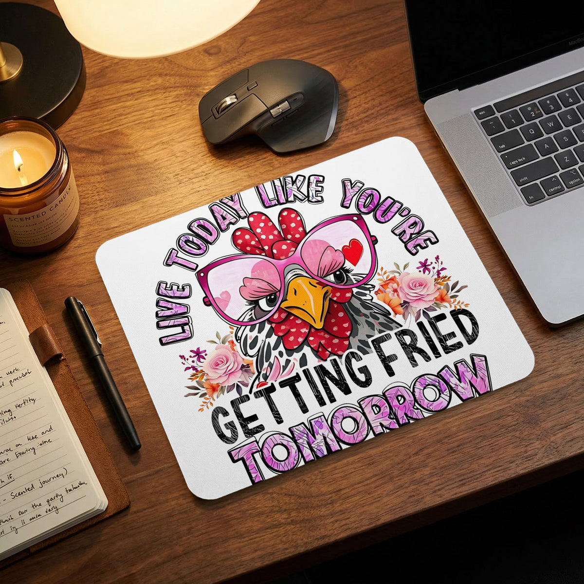 A white mousepad featuring a chicken wearing pink glasses and the text Live Today Like You're Getting Fried Tomorrow rests on a wooden desk.