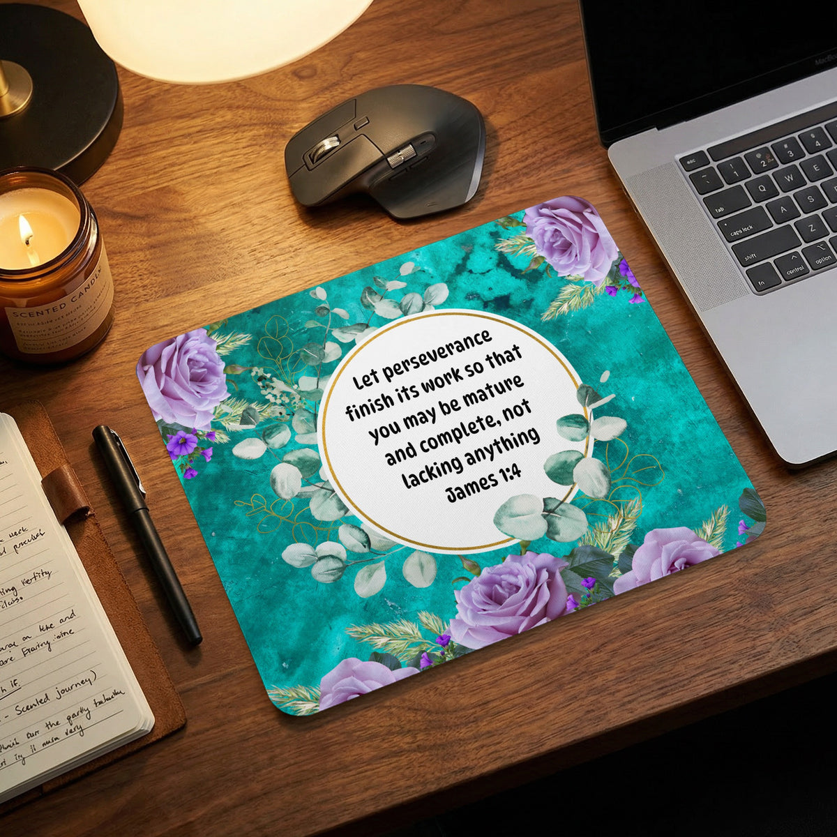 Teal mousepad featuring purple roses, eucalyptus leaves, and an inspirational Bible verse on a wooden desk.