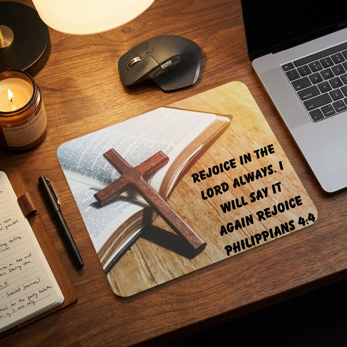 A wooden desk with a mousepad showing an open Bible, a cross, and the text Philippians 4:4.