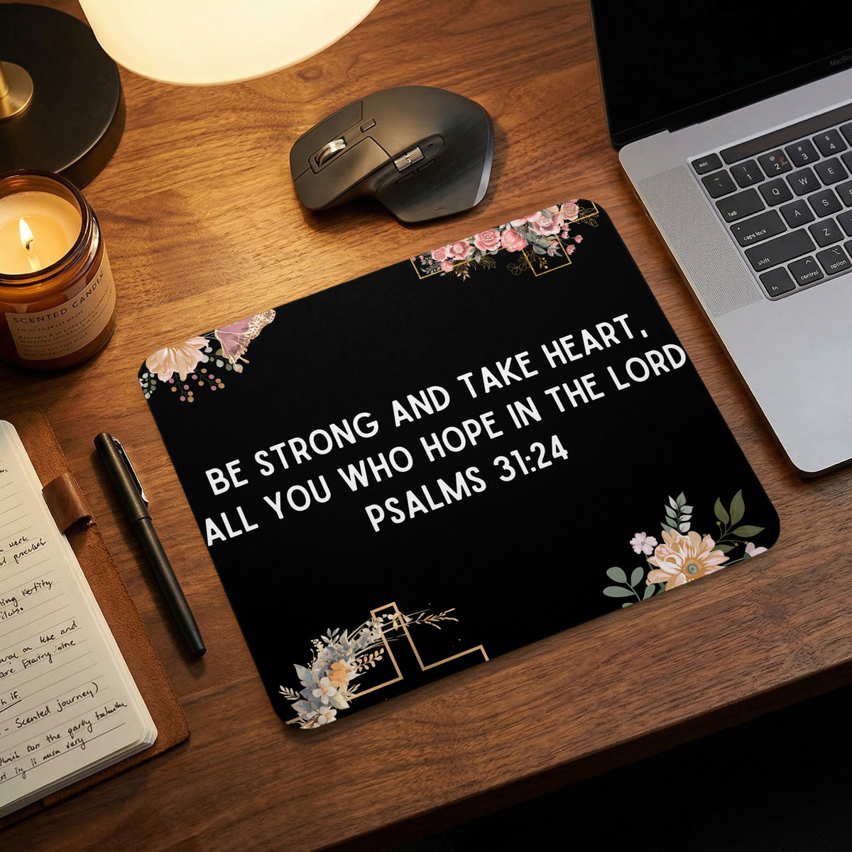 A black mouse pad featuring white text reading Psalms 31:24 rests on a wooden desk.