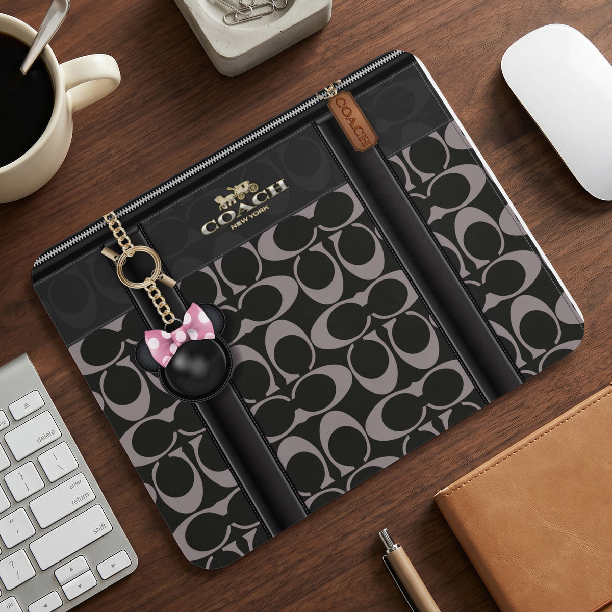 Coach signature print folio with Minnie Mouse charm on a desk.