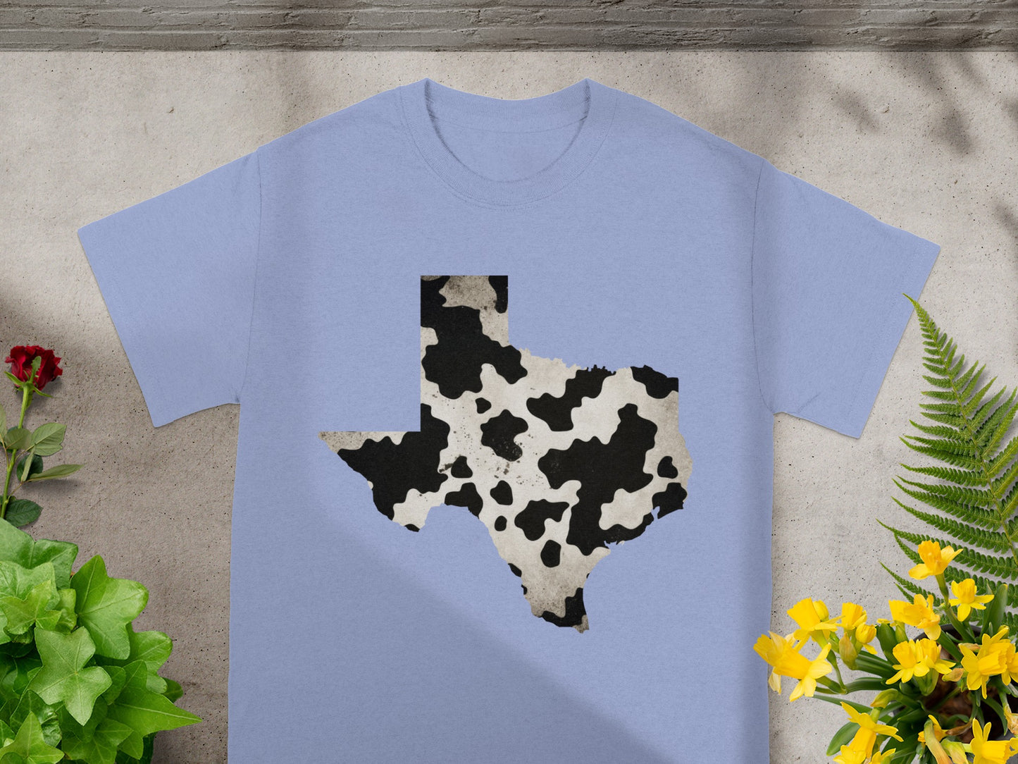 Light blue t-shirt with the shape of Texas and a cow hide pattern.