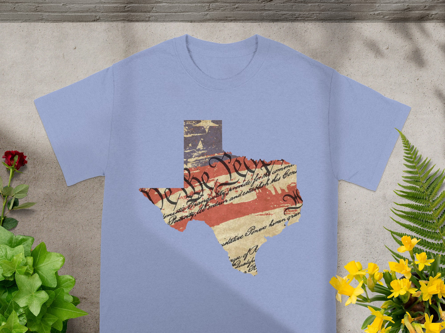 Texas outline graphic with distressed flag and Constitution text elements printed on a pale blue t-shirt.