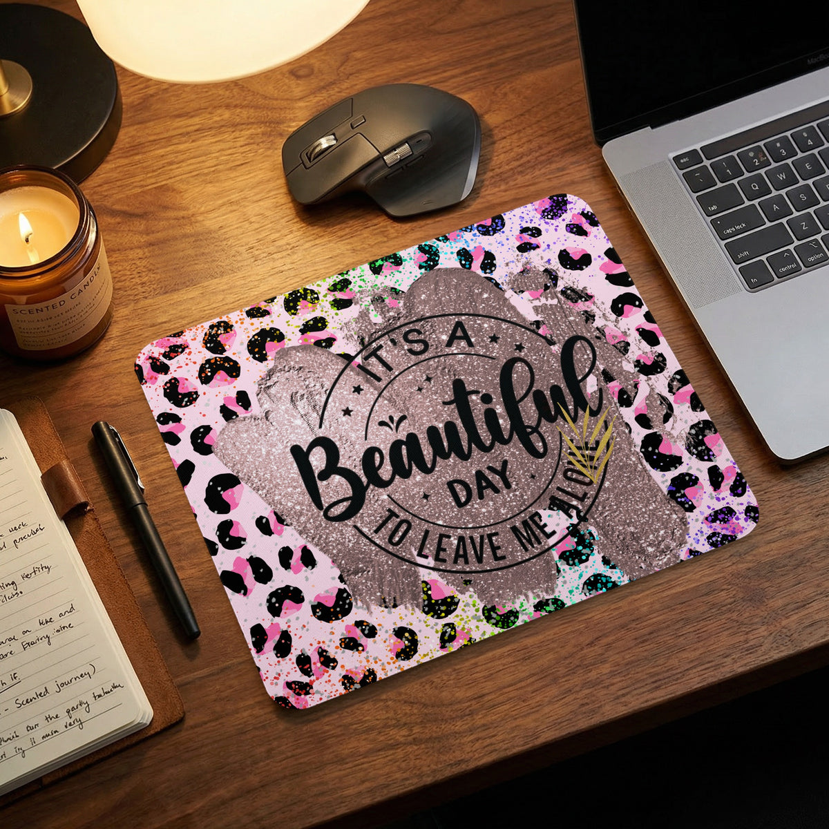 Pink and black leopard print mouse pad featuring the text It's a beautiful day to leave me alone on a wooden desk.
