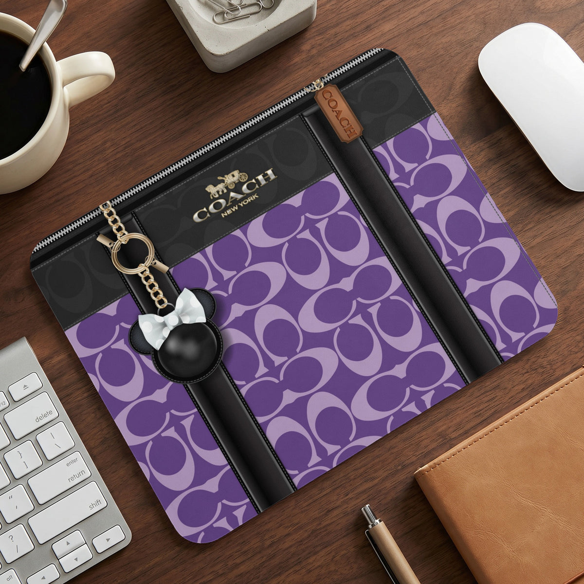 Coach laptop sleeve with purple monogram pattern and Mickey Mouse charm.