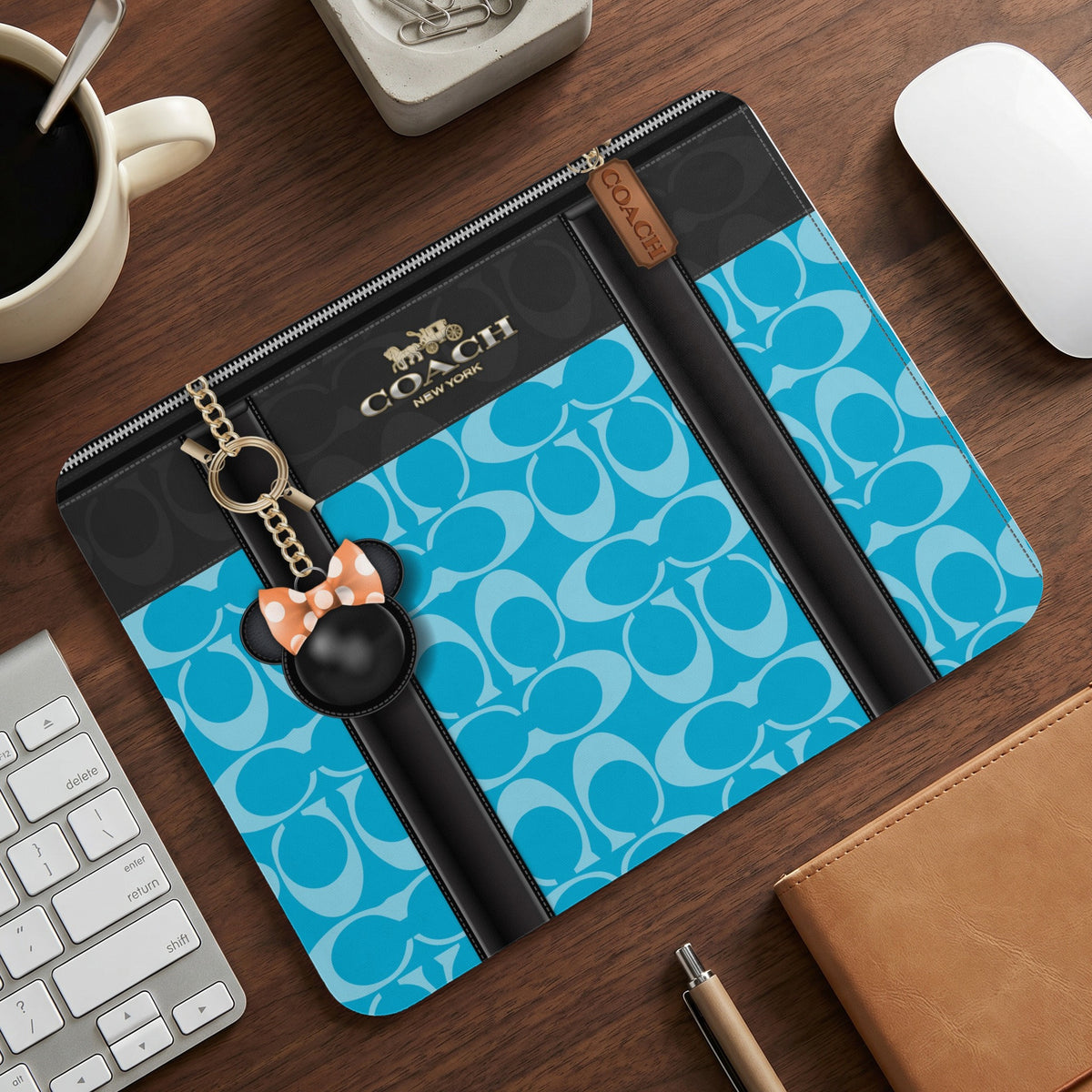 Coach laptop sleeve with blue and white interlocking C logo pattern and Mickey Mouse charm.