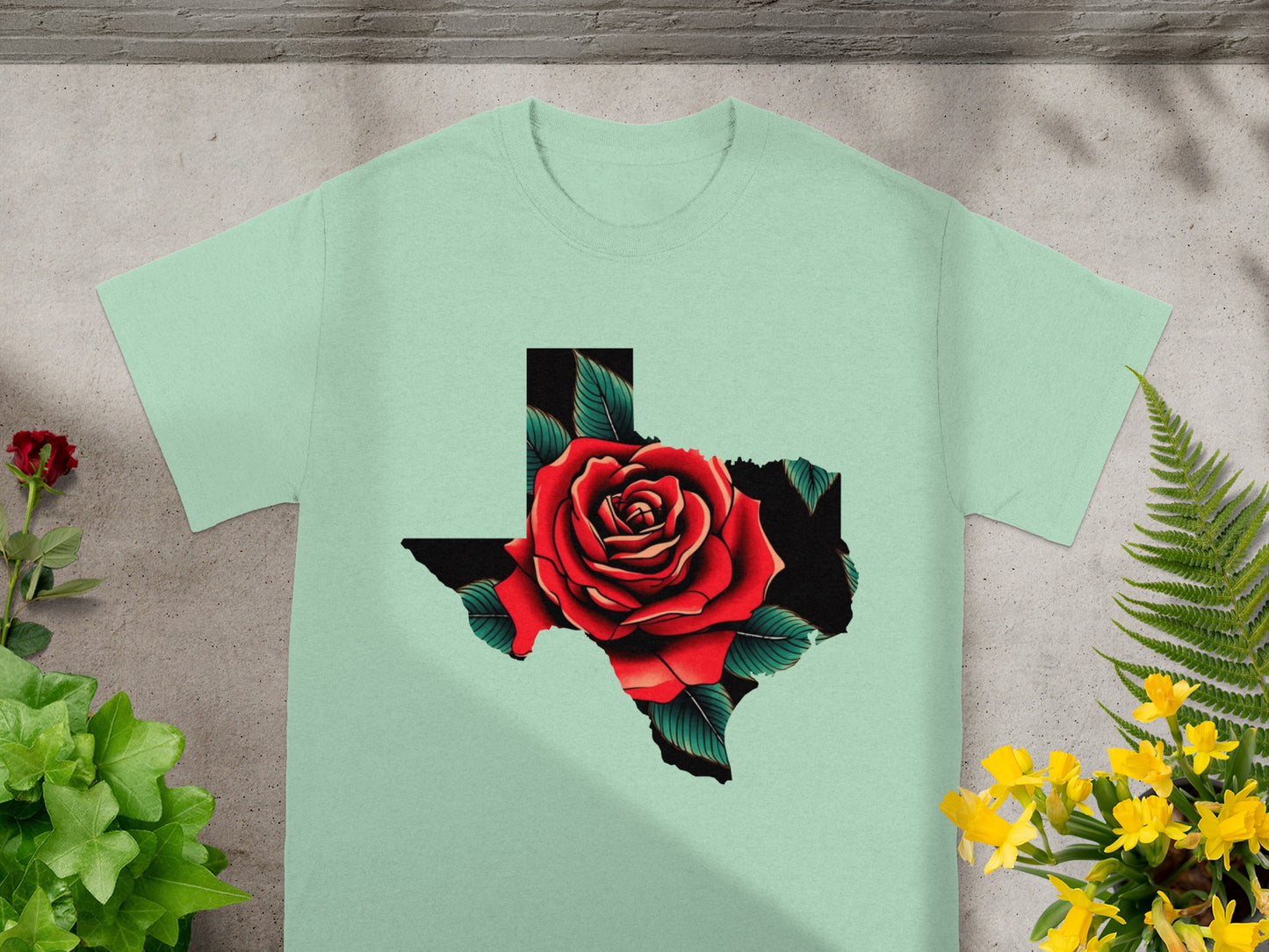 Light green t-shirt with Texas shape filled by a red rose and green leaves.