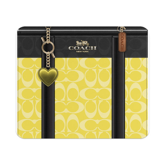 Coach wallet with yellow monogram pattern, gold heart charm, and zipper closure.