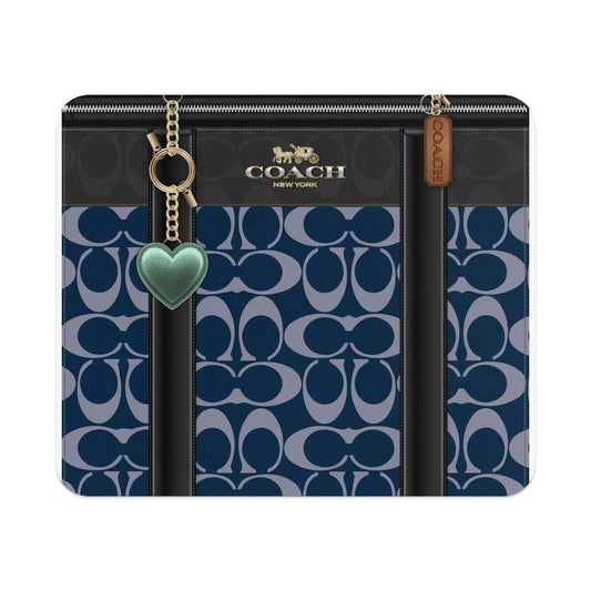 Coach bag with navy signature C pattern, gold hardware, and green heart charm.