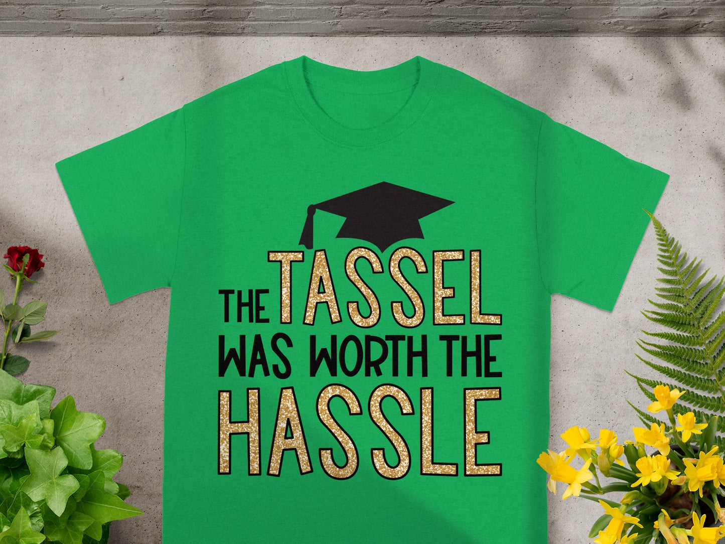 Green t-shirt with "The Tassel Was Worth The Hassle" text and graduation cap design.