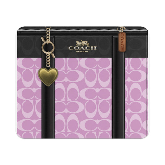 Coach bag detail with pink and black monogram pattern, gold heart charm.