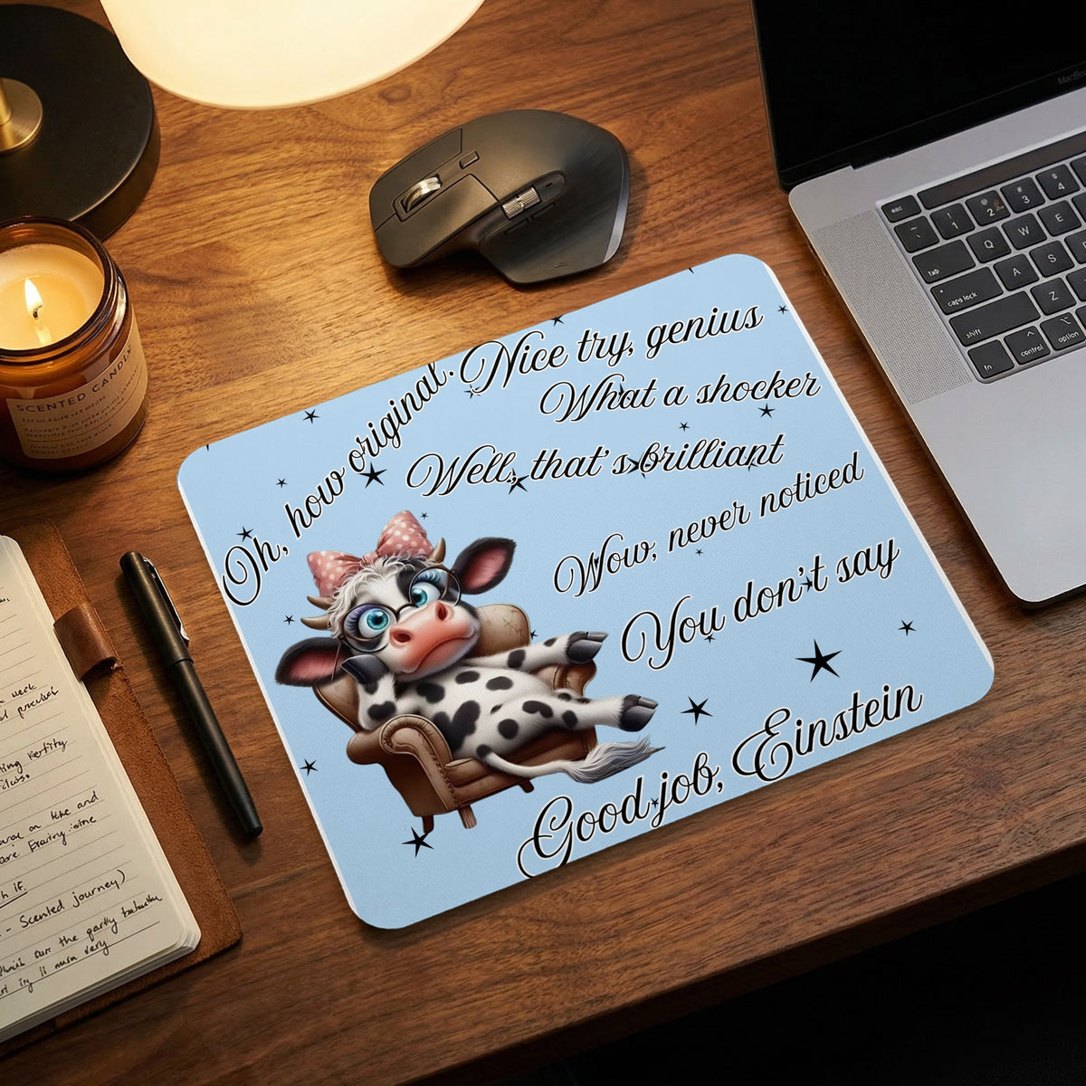 A light blue mousepad featuring a sarcastic cow illustration and sarcastic phrases on a wooden desk.