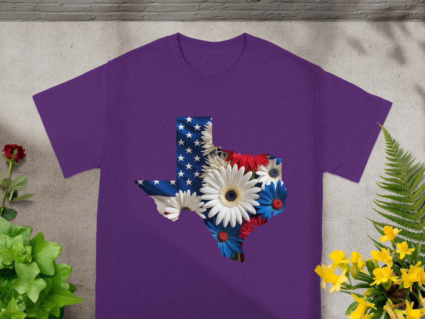 Purple t-shirt with Texas shape filled with American flag and patriotic flowers.