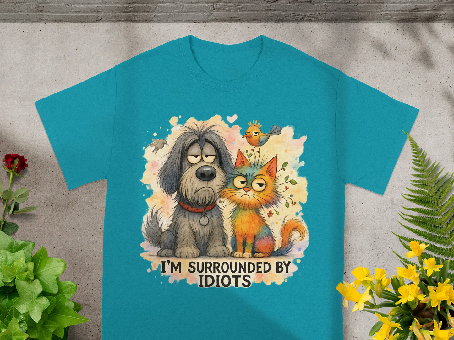Teal t-shirt with cartoon dog and cat saying "I'm surrounded by idiots."