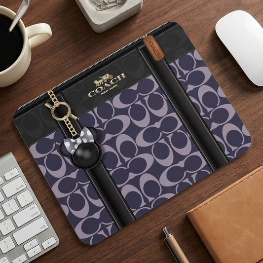 Coach laptop sleeve with signature C pattern, Mickey Mouse charm, and gold hardware.