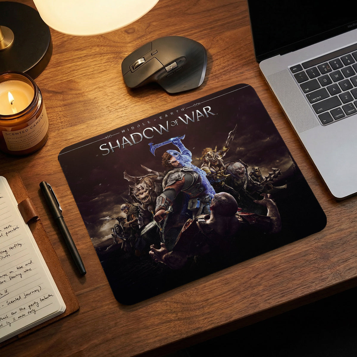 A black mousepad featuring the Middle-earth: Shadow of War video game artwork on a wooden desk.