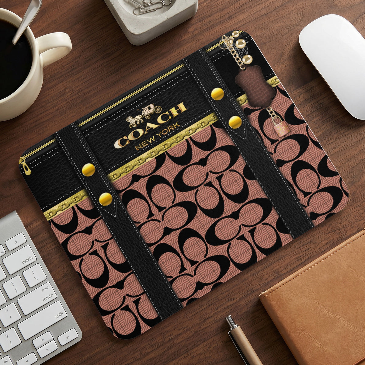 Coach print mousepad with gold hardware and zipper details on wood surface.