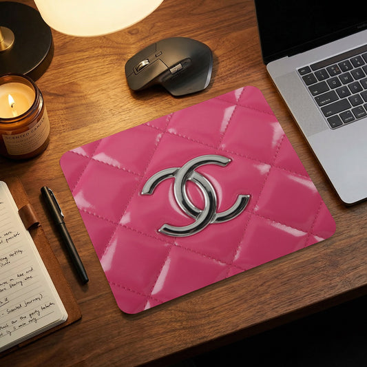 Pink quilted mousepad with interlocking CC logo on a desk.