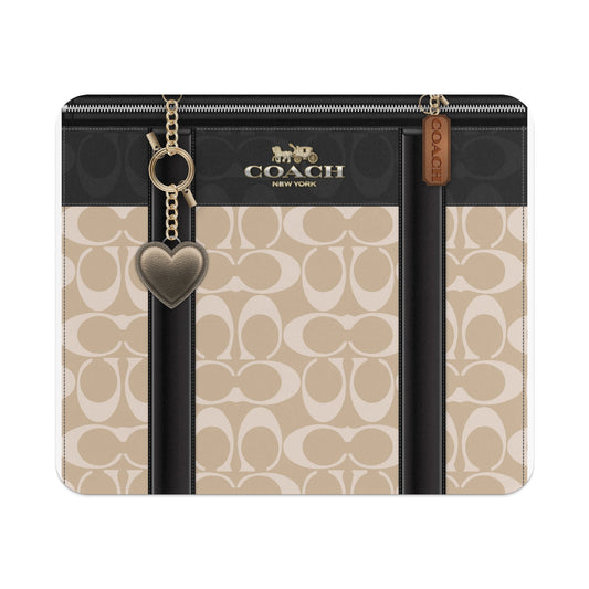 Coach monogram pattern bag with leather trim, gold chain, and heart charm.