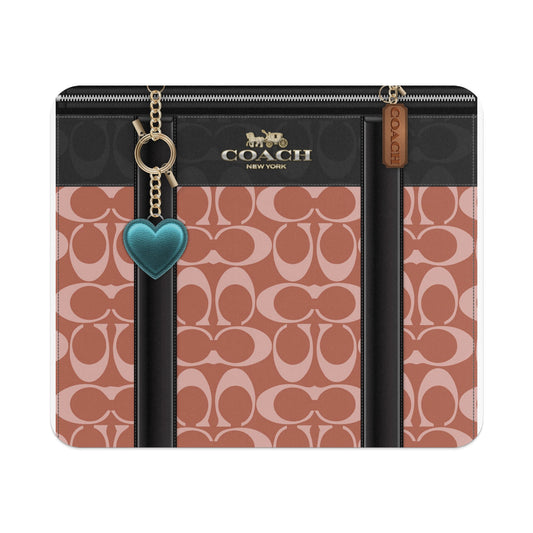 Coach monogram pattern clutch with gold hardware and teal heart charm.