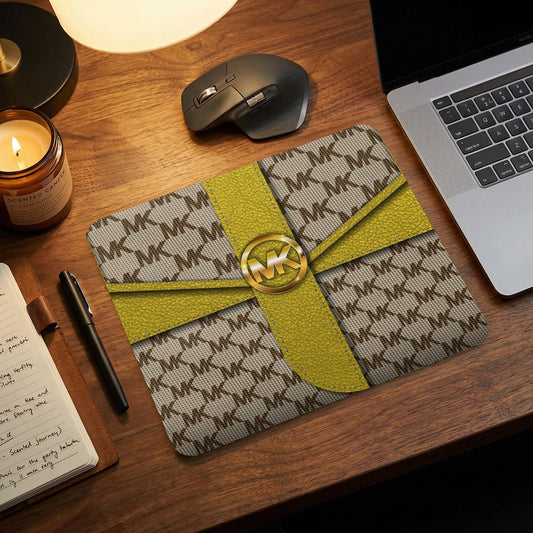 Mousepad with repeating MK pattern, gold ribbon, and MK logo buckle.