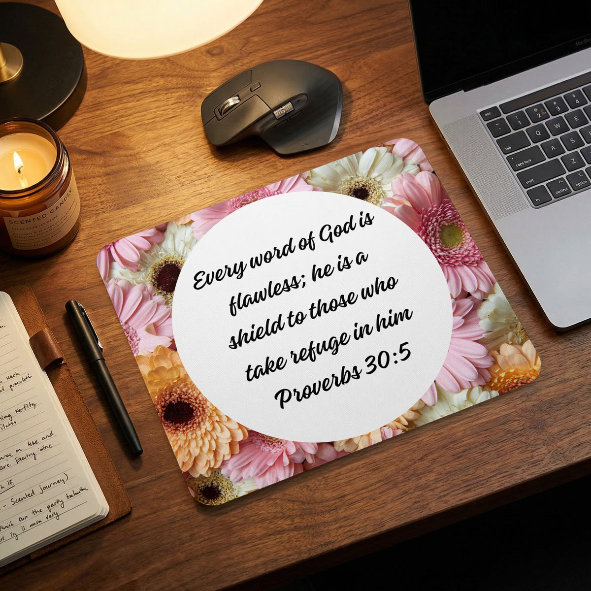 A floral mouse pad featuring Proverbs 30:5 lies on a wooden desk next to a laptop.