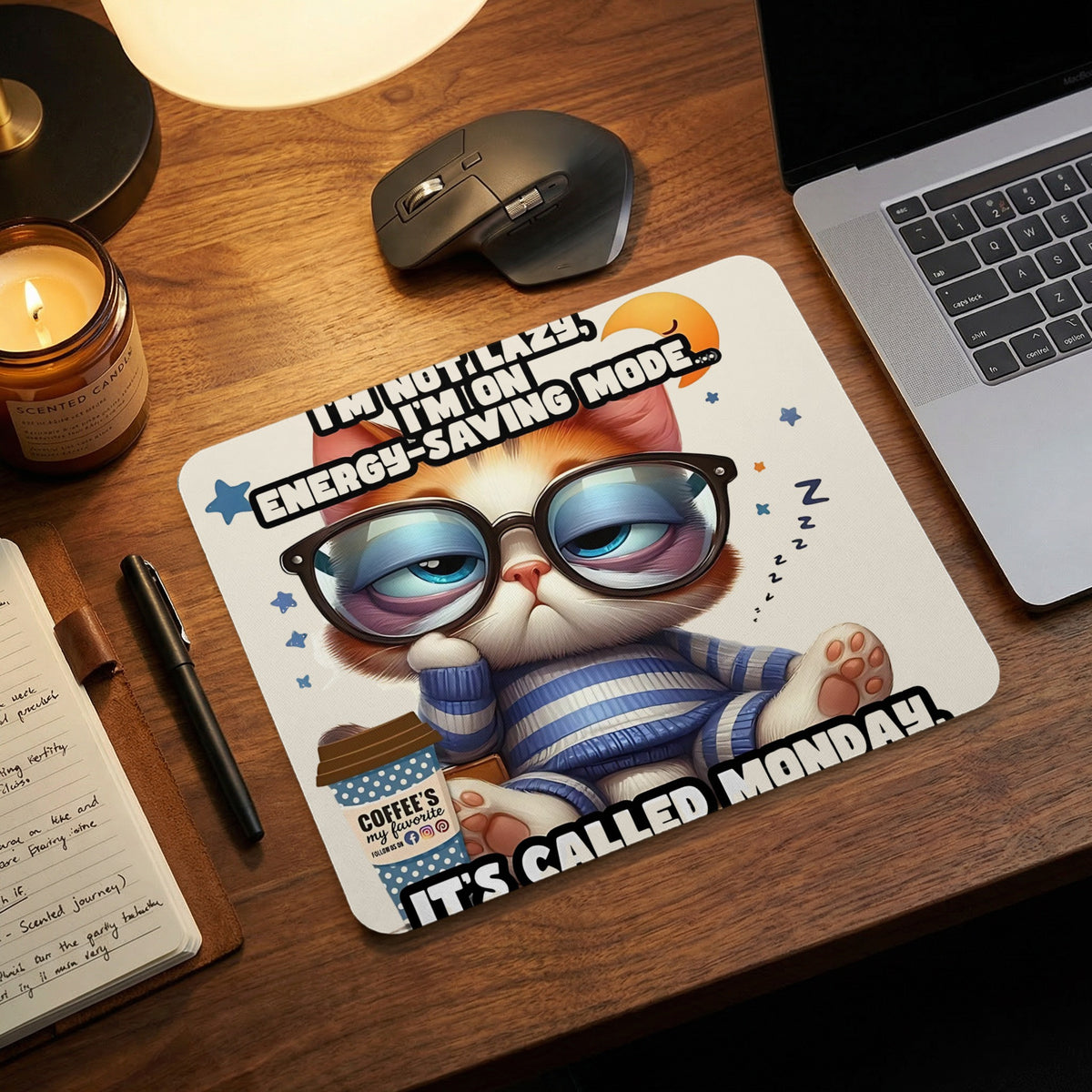 A white mousepad on a wooden desk features a tired cat in glasses, sleep symbols, and text about Monday.