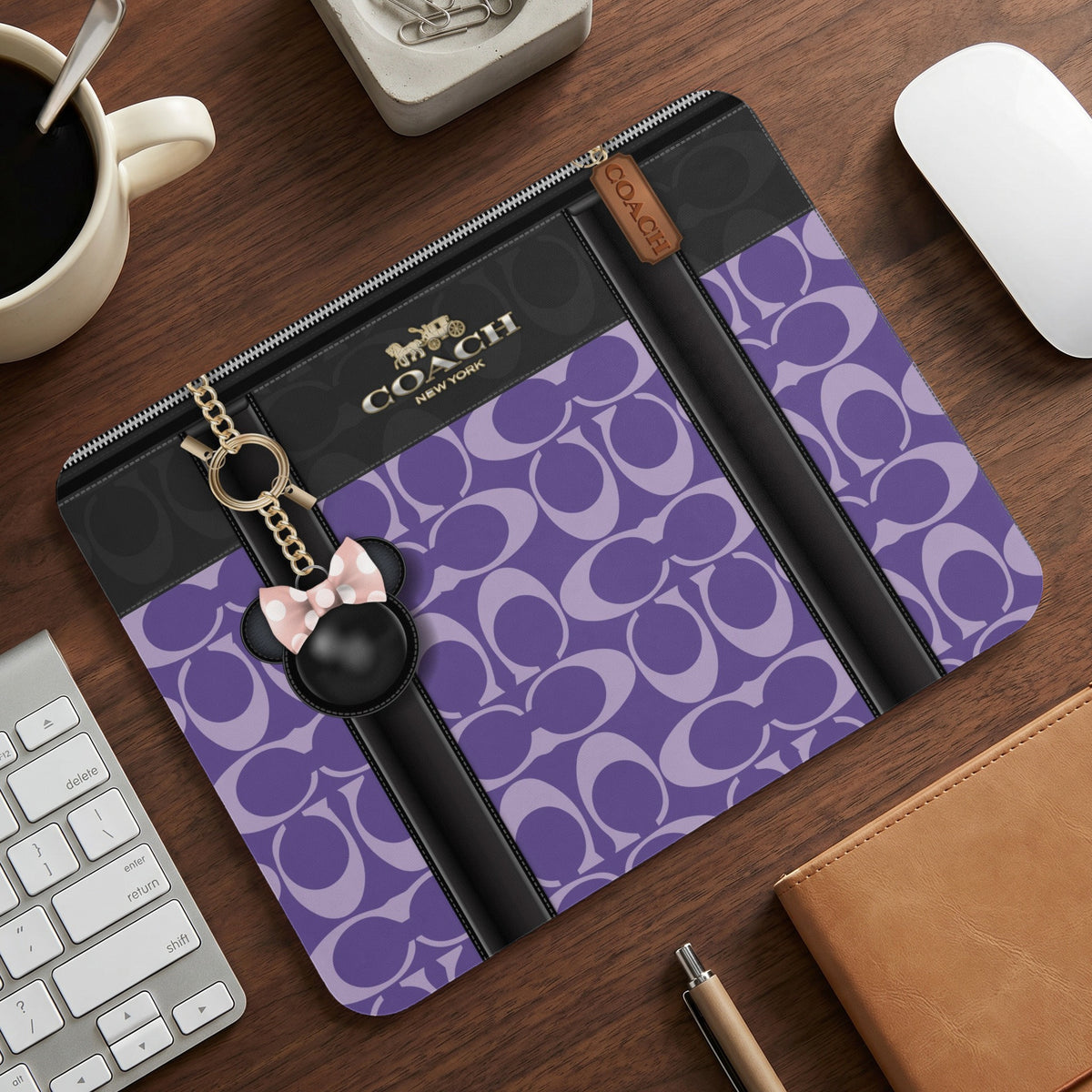 Purple Coach print laptop sleeve with a Mickey Mouse charm and chain.