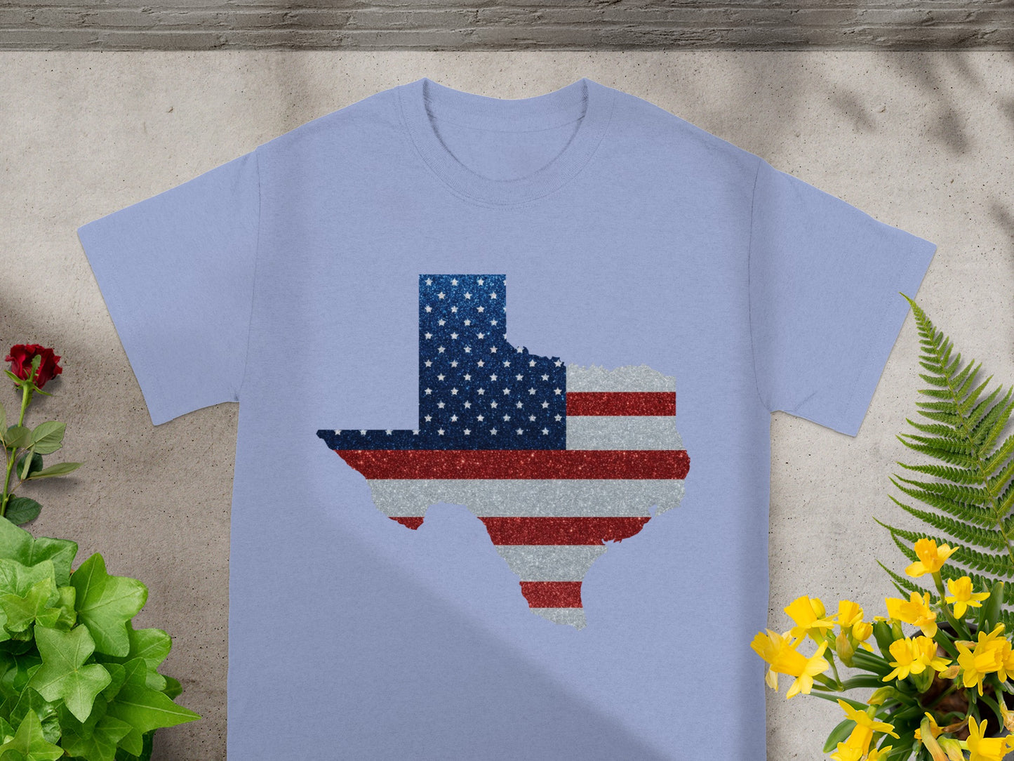 Light blue t-shirt with Texas outline filled with American flag glitter detail.