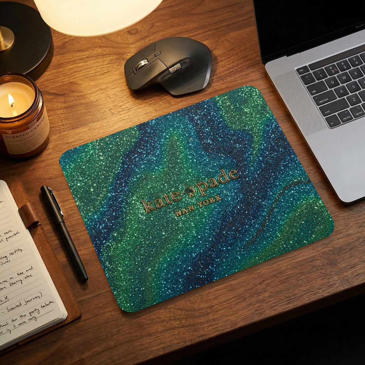 Kate Spade mousepad with glittery green and blue galaxy design and gold logo.