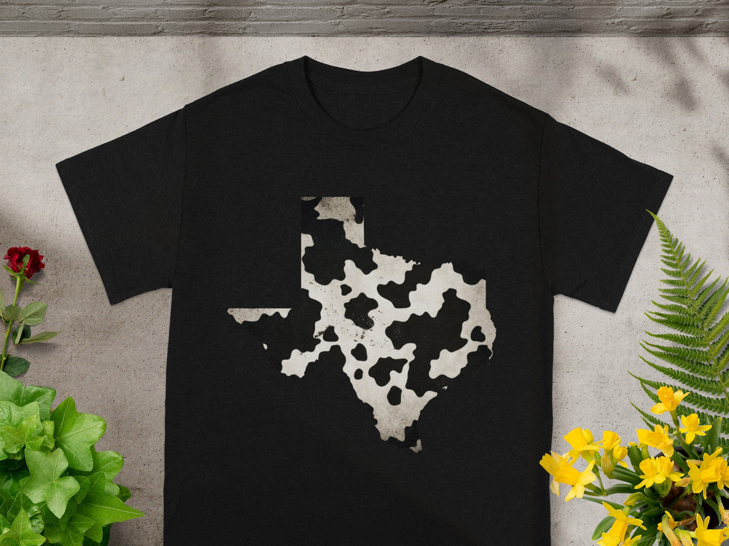 Black T-shirt with a cow print Texas shape graphic.