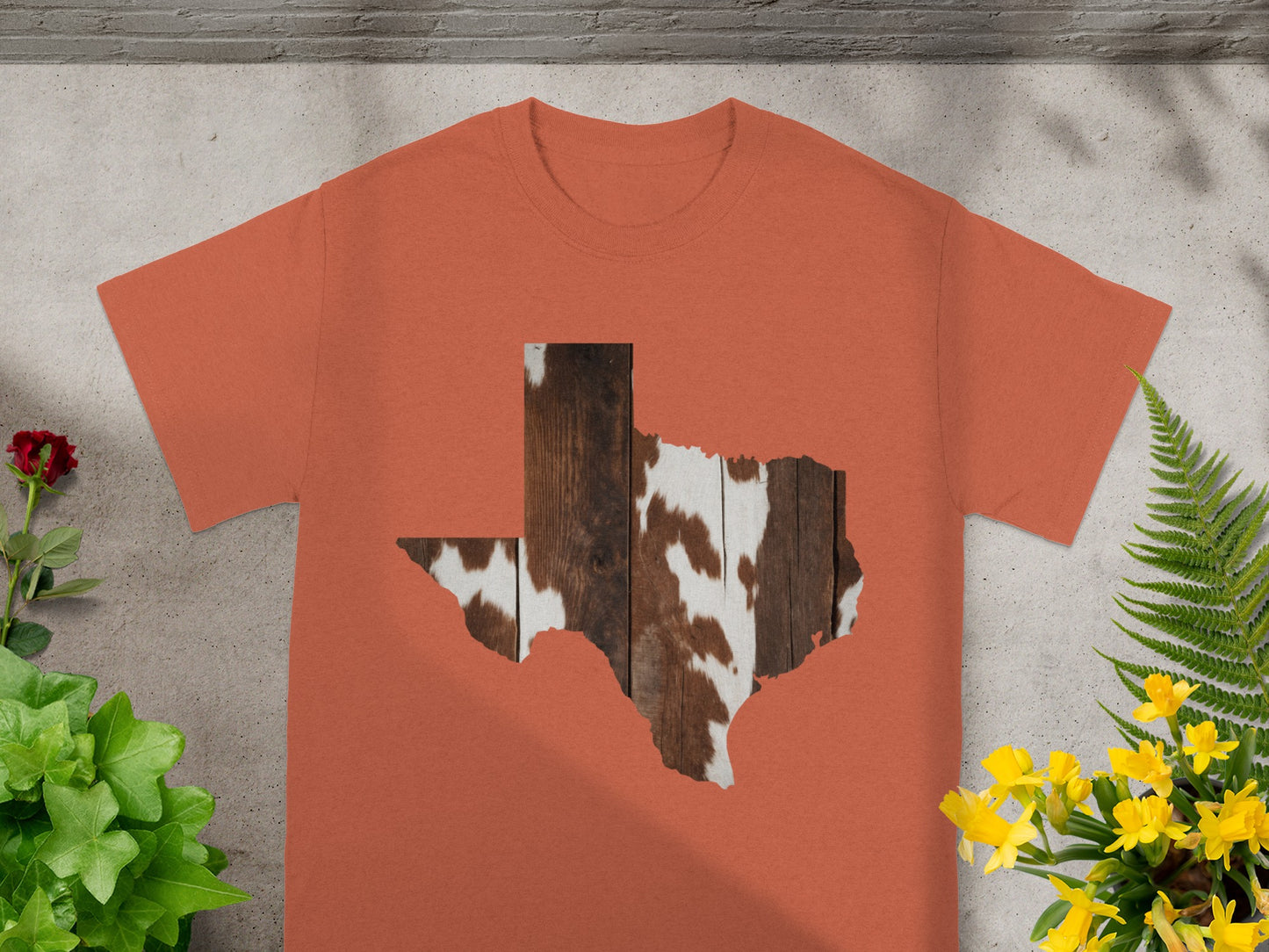 Orange t-shirt with Texas shape cutout showing wood grain and cowhide texture.