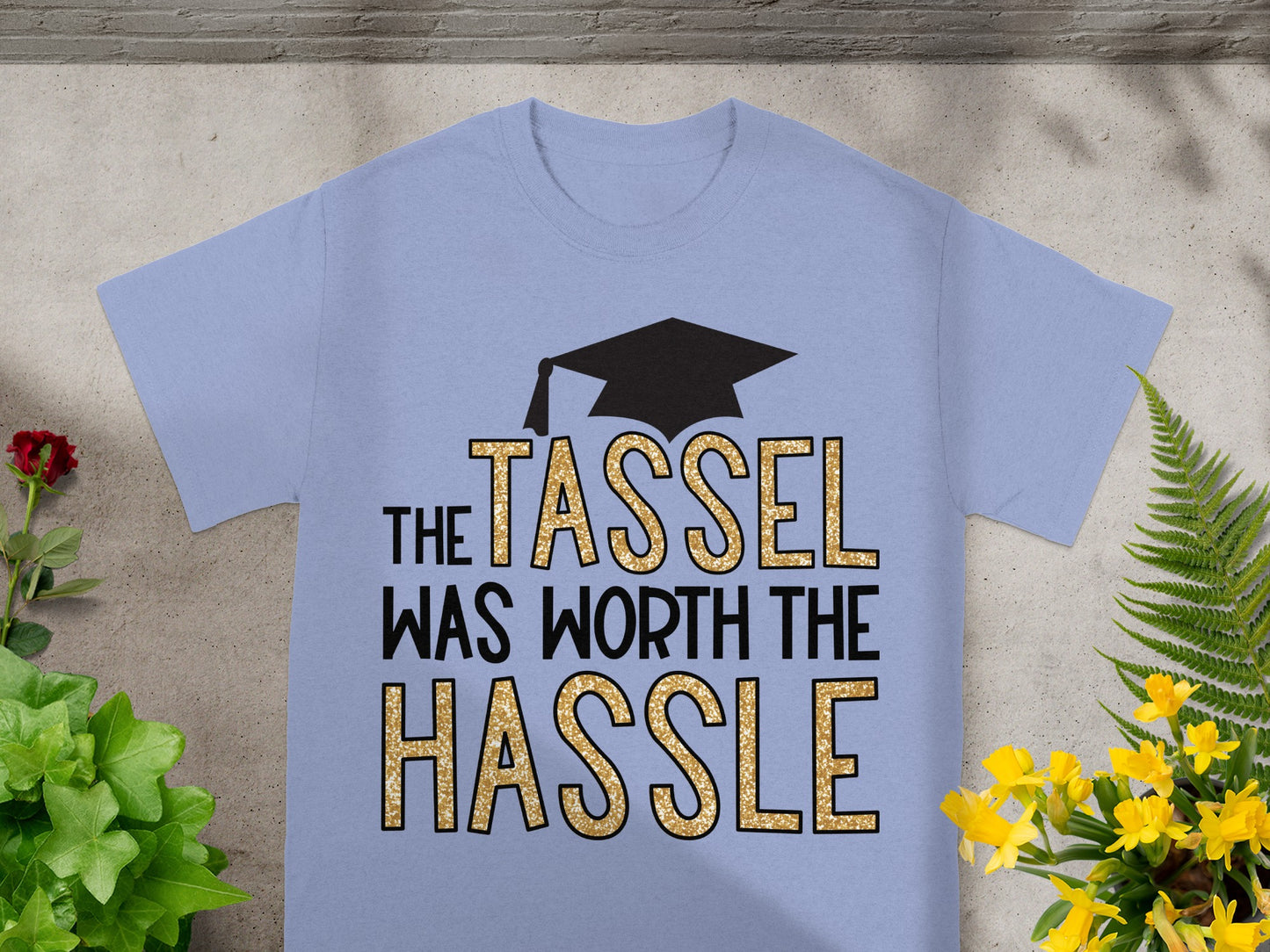 Light blue t-shirt with black graduation cap and gold glitter text.