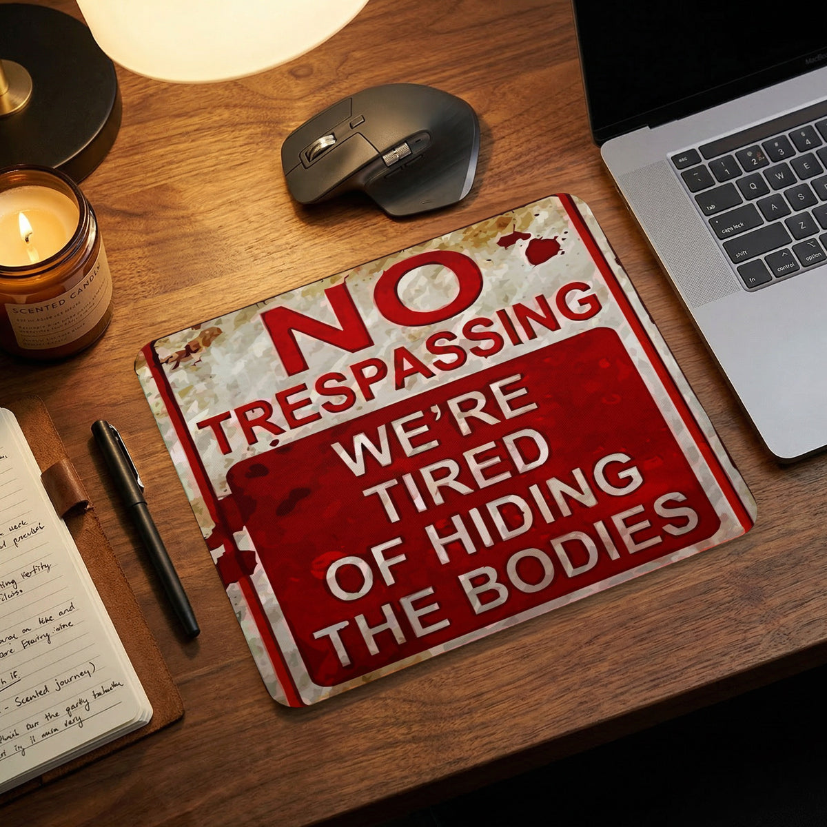 Mouse pad on a wooden desk featuring a humorous, distressed sign that reads, No Trespassing.