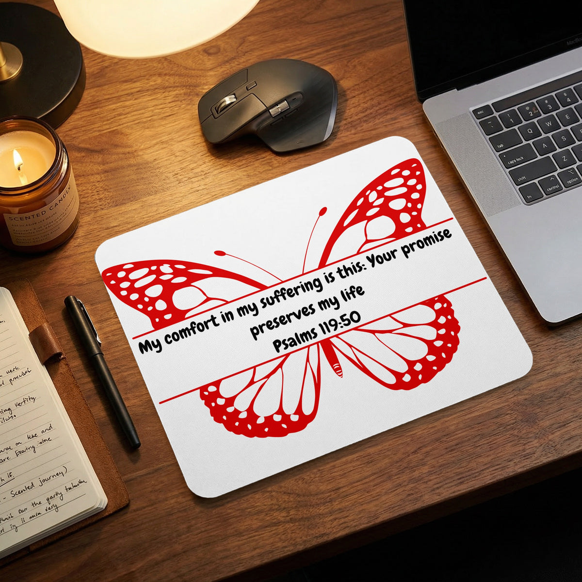 A white mousepad featuring a red butterfly graphic and the Bible verse Psalms 119:50 rests on a wooden desk.