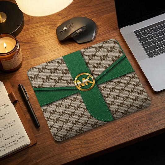 MK pattern mousepad with gold logo, green accents, on wooden desk.