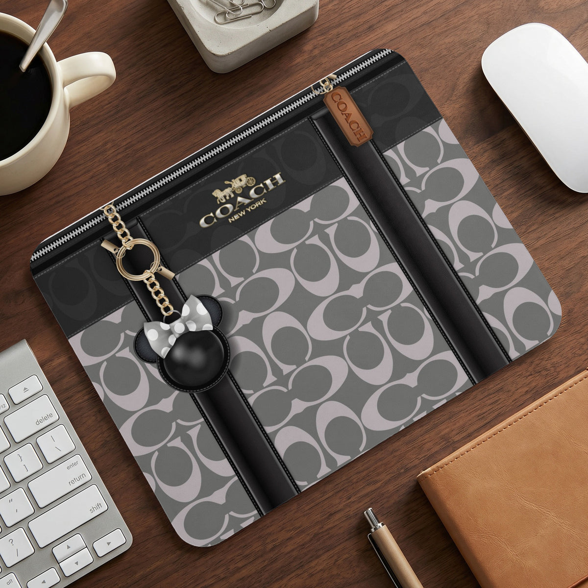 Coach laptop sleeve with signature "C" pattern and Mickey Mouse charm.