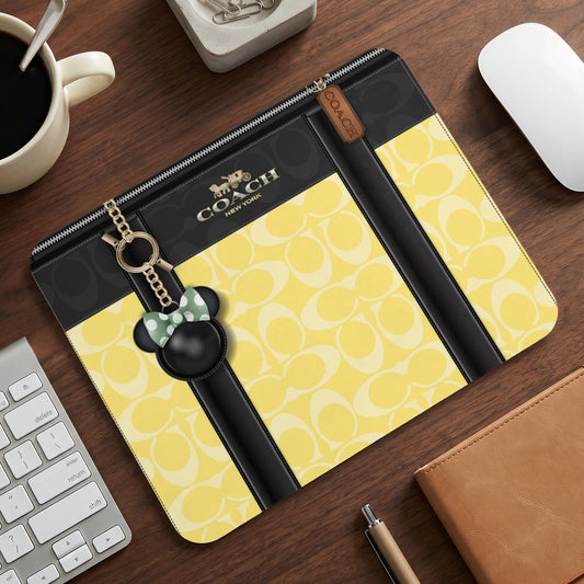 Coach laptop sleeve with yellow C print and Minnie Mouse keychain.