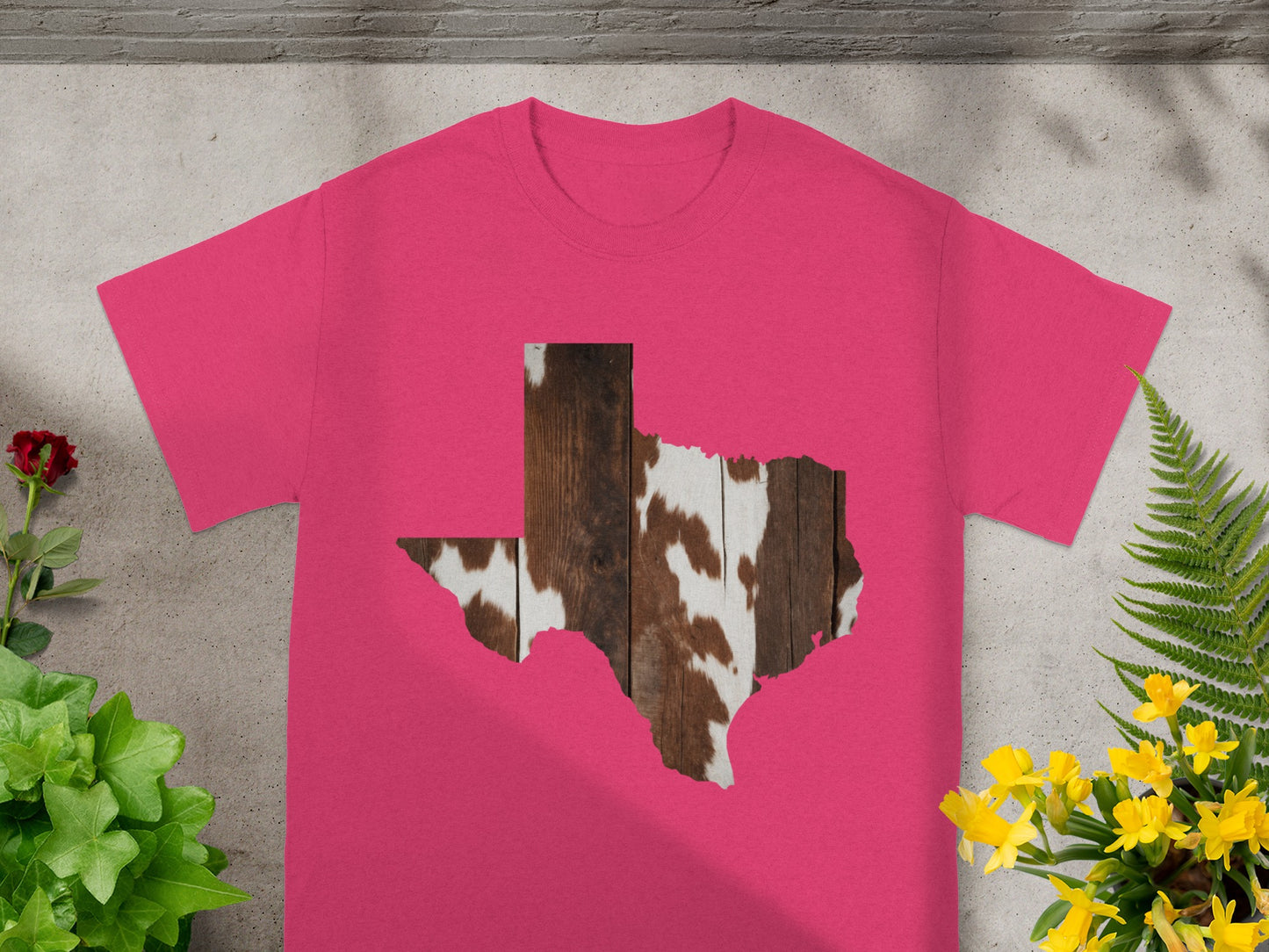 Pink t-shirt with a Texas outline filled with cowhide and wood texture.